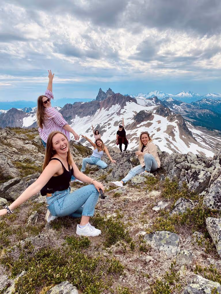 Friends enjoying scenic mountain view with snow-capped peaks and rocky terrain